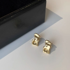 Detailed view of gold lava earrings with irregular wave texture and polished finish