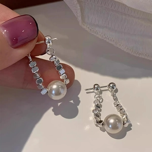 Dettaglio di orecchini a nappa a U in argento S925 con perle e blocchi metallici géo