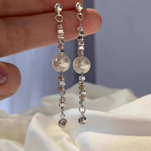 Dettaglio di orecchini a nappa in argento S925 con perline geometriche e grandi perle bianche