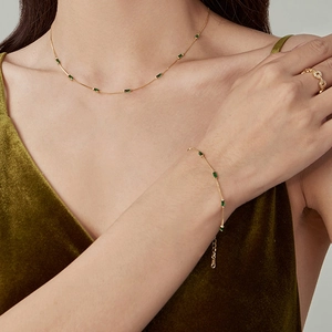 Close-up of elegant gold chain jewelry set with emerald green rectangular gemstones