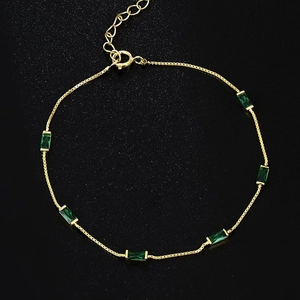 Elegant gold bracelet featuring rectangular emerald green stones and adjustable lobster clasp