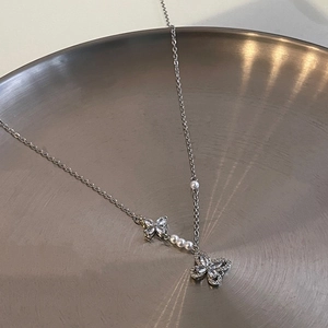 Détail du collier noeud argenté avec zircons brillants et perles blanches délicates