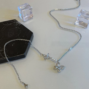 Collier perles avec nœud argenté et pendentif cristal sur marbre et glace