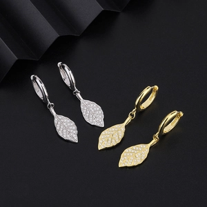 Elegant gold and silver leaf hoop earrings with micro-pave crystals on a black pedestal