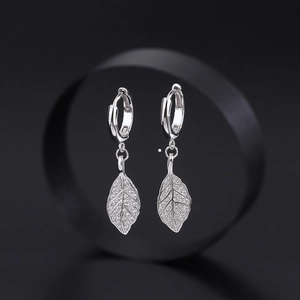 Elegant silver leaf hoop earrings with shimmering white zircon pavé on black background