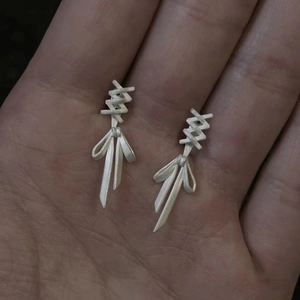Close-up of S925 silver bow ribbon earrings with matte finish and deconstructed design