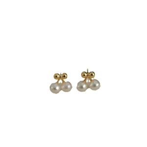 Close-up of elegant cherry pearl stud earrings with gold bow and white pearlescent finish