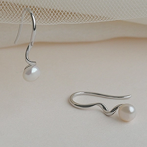 Detail of S925 silver wave earrings featuring elegant white pearls on a soft cream background