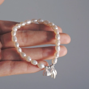 Detailansicht von s925 Silber Lotusanhängern an einem zarten Süßwasserperlenarmband