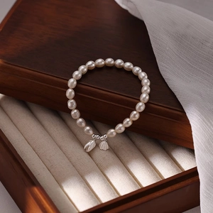 Eleganteres s925 Silber-Perlenarmband mit Tulpenanhänger auf einer Vintage-Schmuckschatulle