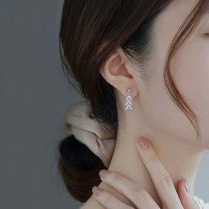 Détail de boucles d'oreilles feuilles en argent S925 avec zircone sur modèle féminin