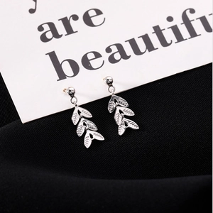 Boucles d'oreilles feuilles en argent S925 avec texture évidée sur fond sombre élégant