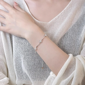 Detail of silver clover bracelet with sparkling diamonds on a woman's wrist