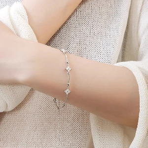 Detail of silver clover heart bracelet with cubic zirconia on a knitted sweater sleeve