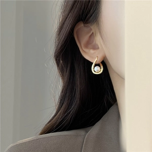 Elegant gold drop-shaped spiral earrings with white pearl inlay on model