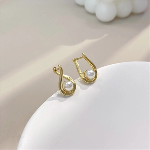 Spiral hollow gold earrings with pearl accents on a minimalist white display stand