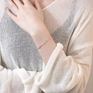 Rose gold bracelet with four-leaf floral diamond charms on a model's wrist
