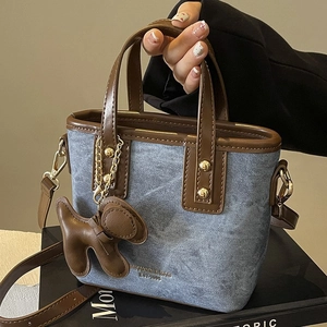 Retro bucket bag in light blue denim with brown leather trim and a cute puppy charm