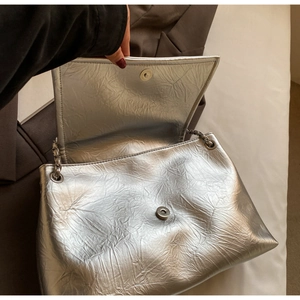 Close-up of silver pleated shoulder bag showing magnetic closure and chain strap