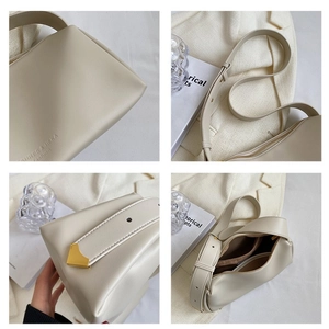 Minimalist beige leather shoulder bag with gold metal corners and wide strap