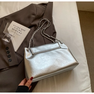 Detailed macro view of silver metallic pleated texture and chain strap on a chic tote bag