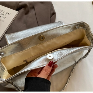Interior detail of silver metallic tote featuring magnetic closures and inner zip pocket