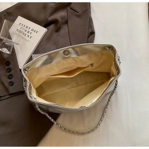 Detail view of silver metallic shoulder bag interior with magnetic clasp and chain strap