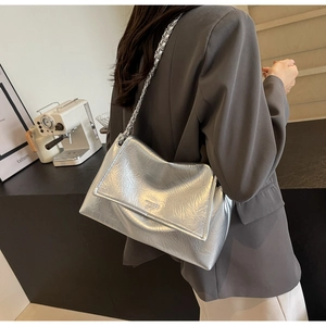 Close-up of metallic silver shoulder bag with embossed texture and chain strap