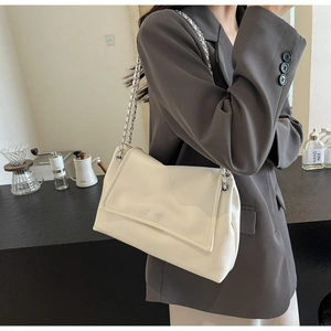 Detail of the cream-colored tote bag with textured finish and silver chain strap