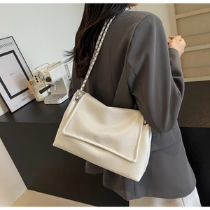 Detail of white pleated leather bag with silver chain strap and logo on grey blazer
