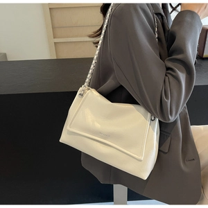 Detail of white glossy patent leather tote with silver chain strap and logo lettering