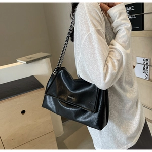Close-up of black PU leather shoulder bag with silver chain strap and metal brand logo