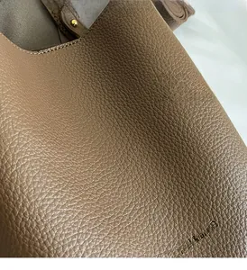 Detail of brown litchi pattern leather bucket bag with precise stitching and gold hardware
