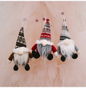 Detailed view of three knitted Christmas gnomes with long white beards and hanging strings