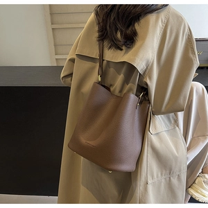 Detail of dark brown lychee leather bucket bag with gold ring and fashion embossing