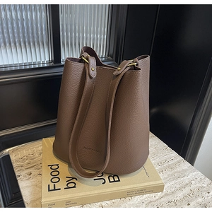 Detail of brown litchi leather bucket bag showing the texture and gold rivet hardware