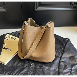 Detail of brown lychee grain leather bucket bag with gold buckle and embossed text