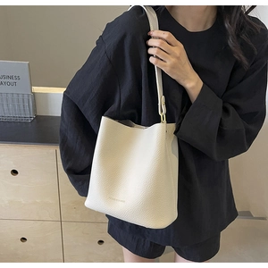 Detail of creamy white lychee grain leather bucket bag with FASHION & BAGS logo