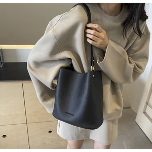 Detail of black lychee grain leather bucket bag with gold hardware and shoulder strap