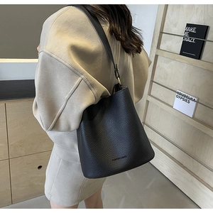 Black pebbled leather bucket bag shown from a side-back view on a model for daily use