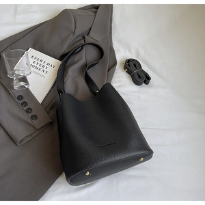 Detail of black lychee grain leather bucket bag with gold rivets and fashion logo