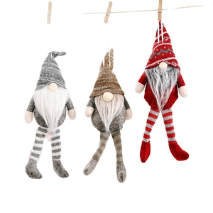 Three Christmas gnome ornaments with long legs hanging on a rope against a white background