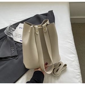 Detailed view of beige bucket bag with lychee grain texture and adjustable shoulder strap
