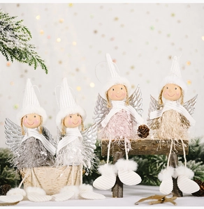 Close-up of four plush Christmas angel ornaments with fuzzy wings on a wooden bench
