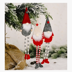 Close-up of three long-legged Christmas gnomes hanging on a festive decorated pine tree