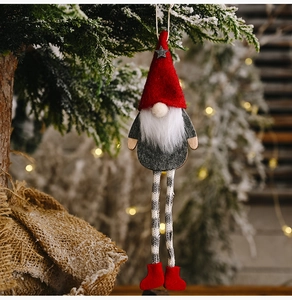 Hanging Christmas gnome ornament with red felt hat and striped legs on pine branch