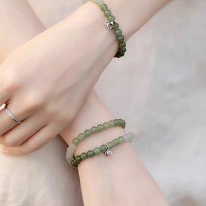 Detailed shot of green jade bead bracelet with silver lotus pendant and textured ring