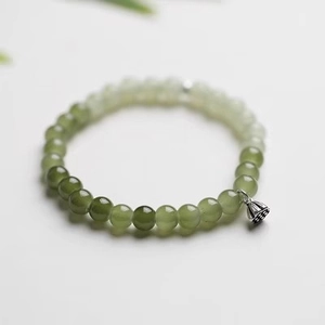 Detail of gradient green jade beads with a silver lotus seed pod charm pendant
