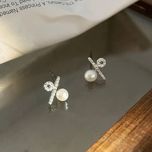 Macro shot of asymmetric percentage earrings with silver metal, pearls and pavé stones