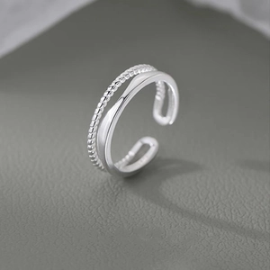 Detail of silver twisted double-layer open ring with minimalist woven texture